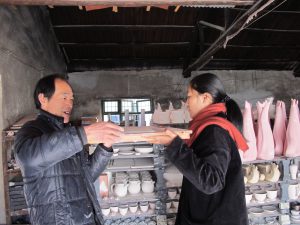 De 'kilnman' en 'pottery workshop assistent Snow' schuiven samen kleiplaat voor lunchproject in de 'public kiln'